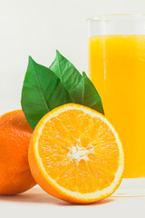 A cup of orange juice and cut orange on  white background.
