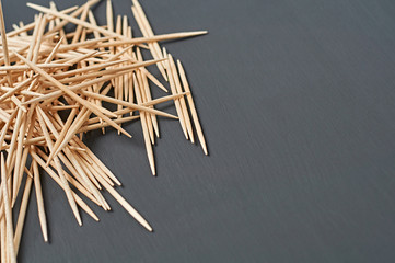 Heap of wooden toothpicks lies on black concrete desk on kitchen. Space for text