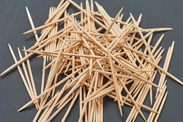 Heap of wooden toothpicks lies on black concrete desk on kitchen. Close-up