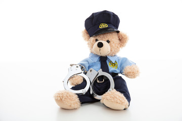 Cute teddy in policeman uniform and handcuffs isolated against white background