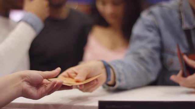 Tracking shot with mid-section of unrecognizable man paying for movie tickets at cinema