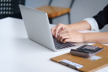 Businesswoman  working with laptop on wood desk at office. Woman typing on computer laptop keyboard on desk wooden.