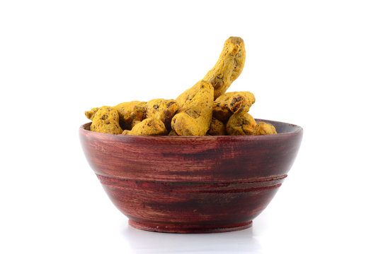 Dry Turmeric roots or barks in wooden bowl isolated on white background