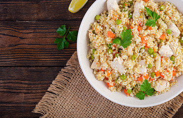 Bulgur with chicken, green peas and carrot  on wooden background. Top view