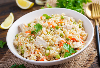 Bulgur with chicken, green peas and carrot  on wooden background.