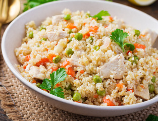 Bulgur with chicken, green peas and carrot  on wooden background.