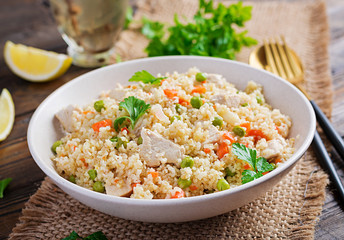 Bulgur with chicken, green peas and carrot  on wooden background.