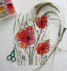 Cross stitch flowers. Watercolor red poppies on canvas in a wooden Hoop. Girl embroiders a cross stitch.