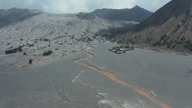 Aerial drone view flying over the black sea of volcanic sand and old lava flows around the Mount Bromo active volcano in Indonesia
