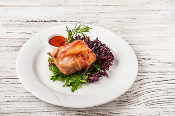 Quail stuffed in a restaurant close-up. Quail in bacon on a white plate and copy space.
