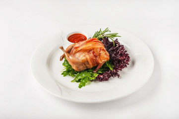 Quail stuffed in a restaurant close-up. Quail in bacon on a white plate and copy space.