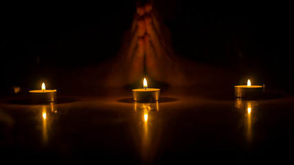Praying in the dark with three lighted candles.