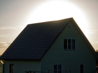 very bright sun from behind the roof of the house, Russia.