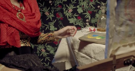 Close up of Frida Kahlo sitting down at the table and starts painting, 4k