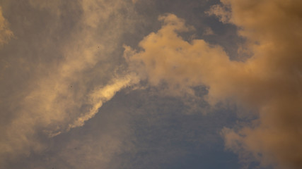 Fototapeta na wymiar Orange color fluffy clouds on sunset time under dark blue sky
