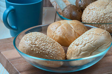 wheat buns with sesame filling in a glass bowl, a ceramic mug and a bottle of milk on the kitchen table