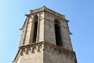 Fototapeta na wymiar Stone Church Tower & Long Windows against Sunny Blue Sky