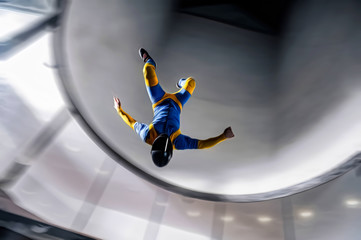 Up. Fly men is a pilot of his body in air. Extreme people prefer skydiving. Parachutist in blue and yellow suit. Free lifestyle.