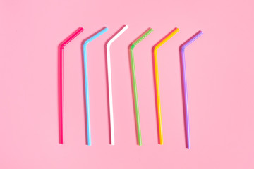 Rows of colorful straws for beverage on pink table. Close-up