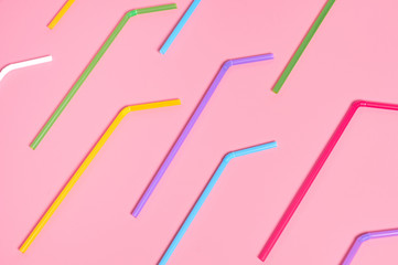 Rows of colorful straws for beverage on pink table. Top view. Close-up