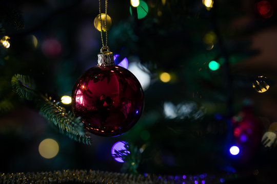 Red christmas ball hanging on a christmas tree with blurred lights on background