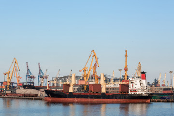 Container Ship. Industrial Container Cargo freight ship with working crane bridge in shipyard at...
