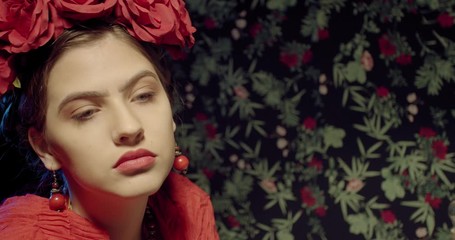 Close up of the face of Frida Kahlo while she is painting, flowers in her hair