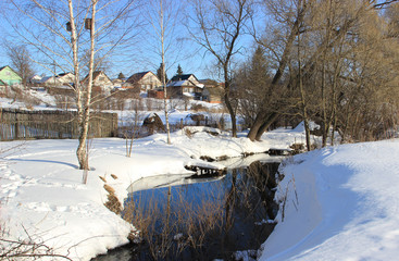 An ice-free stream at the edge of the village. Snow all around.
