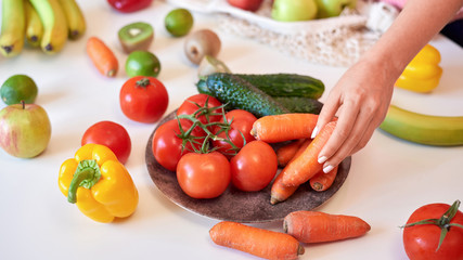 Fototapeta na wymiar White table with woman hands picking carrot
