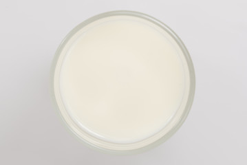 A cup of soy milk stands alone on a pale yellow background.