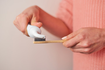 Woman hands squeezing toothpaste on bamboo