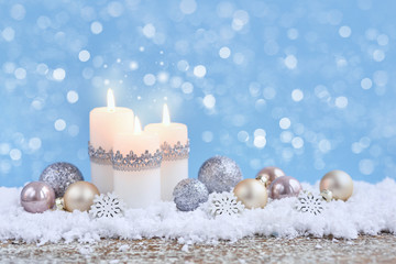 Christmas composition with candles and festive decorative balls on the snow. New Year greeting card.