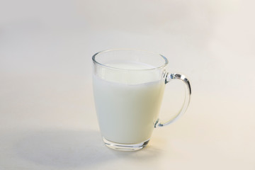 A cup of soy milk stands alone on a pale yellow background.