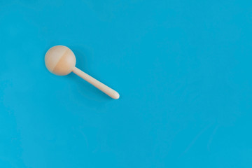 Wooden baby rattle on a blue background. Flat lay, hand made, copy space, top view, toy.