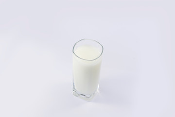 A cup of soy milk stands alone on a pale yellow background.