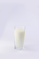 A cup of soy milk stands alone on a pale yellow background.