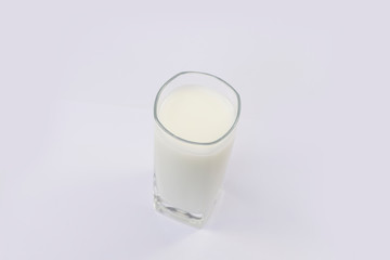 A cup of soy milk stands alone on a pale yellow background.