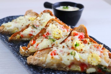 Chili Cheese toast, Open cheese sandwich or mini bread pizzas served with mayonnaise deep and garnished with chopped Basil leaves.