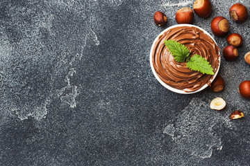 Nougat nut chocolate in a plate on a dark concrete background with hazelnut nuts. Concept of...