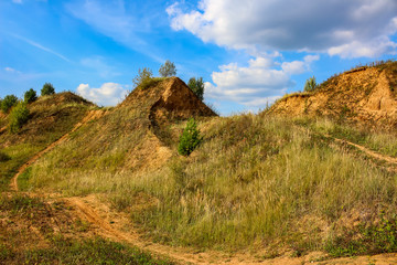 Hilly sandy terrain, part of a motocross track against a blue sky