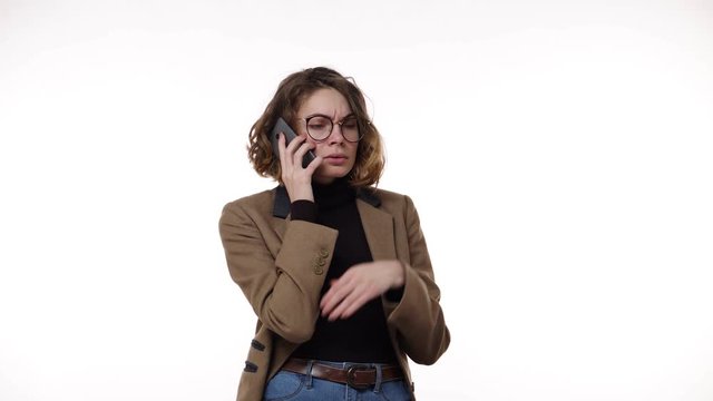 Confused european woman holding cellphone having problem with the calling person, frustrated angry girl received bad news at smartphone annoyed by spam or unwanted call over white background