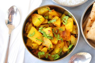 Stainless steel Lunch Box or Tiffin with Indian food menu Chapati or Roti, Garlic Dal Tadka, White Rice and Potato or Jeera aloo. with spoons, tissue paper and glass of water. Copy space