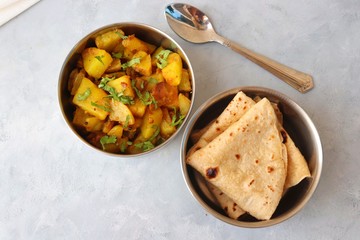 Stainless steel Lunch Box or Tiffin with Indian food menu Chapati or Roti, Garlic Dal Tadka, White Rice and Potato or Jeera aloo. with spoons, tissue paper and glass of water. Copy space