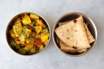 Stainless steel Lunch Box or Tiffin with Indian food menu Chapati or Roti, Garlic Dal Tadka, White Rice and Potato or Jeera aloo. with spoons, tissue paper and glass of water. Copy space