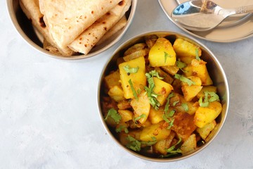 Stainless steel Lunch Box or Tiffin with Indian food menu Chapati or Roti, Garlic Dal Tadka, White Rice and Potato or Jeera aloo. with spoons, tissue paper and glass of water. Copy space