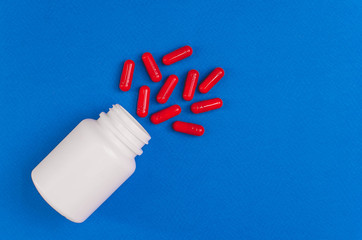 white packaging with red pills on a blue background. view from above.