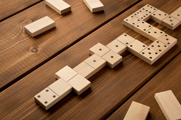 Playing dominoes on a wooden table. Leisure games concept. Selective focus.