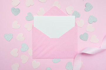 Mock up of blank pink envelope with white sheep of paper. Greeting card with silver confetti hearts and ribbon on wooden pink table on Valentine or mother day