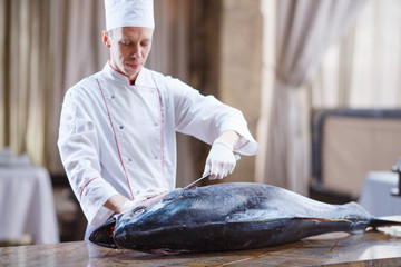 cook cooks big tuna in a restaurant