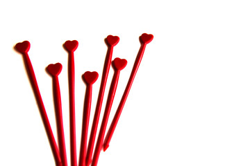 Red plastic sticks for canapes with a heart on a white isolated background. Place for text.